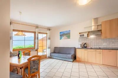 a kitchen and living room with a table and a couch at Weinhof am See in Caldaro