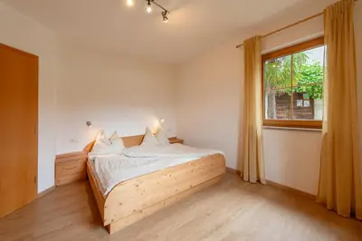 a bedroom with a wooden bed and a window at Weinhof am See in Caldaro