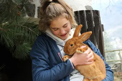 a girl holding a brown rabbit in her arms at Moserhof in Marlengo
