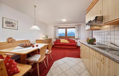 a kitchen and living room with a table and a couch at Perlhof in Schenna