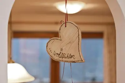 a heart shaped wooden sign hanging from a wall at Perlhof in Schenna