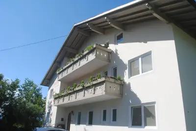 a white building with potted plants on the balconies at Pension Etschland in Tirolo