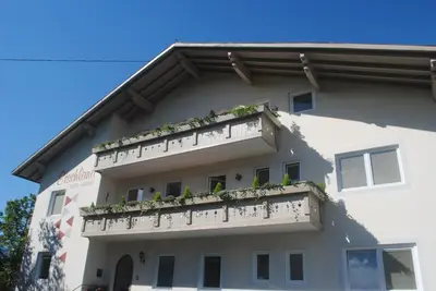 a building with a balcony with plants on it at Pension Etschland in Tirolo