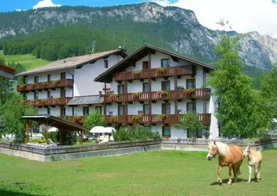 two horses standing in a field in front of a hotel at Appartamenti Astoria La Villa in La Villa