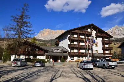 a large building with cars parked in a parking lot at Appartamenti Astoria La Villa in La Villa