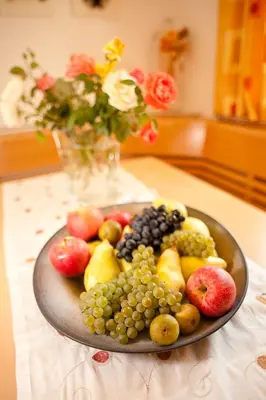 a plate of fruit on a table with a vase of flowers at Villa Trogerhof in Ora/Auer