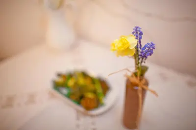 a vase with flowers and a plate of food on a table at Ferienwohnungen Trogerhof in Ora/Auer