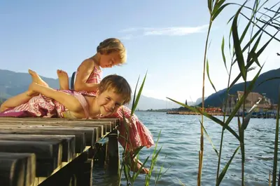two children sitting on a dock in the water at Ferienwohnungen Trogerhof in Ora/Auer