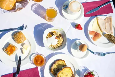 a table with plates of food and cups of coffee at Pension Stamserhof in Nalles