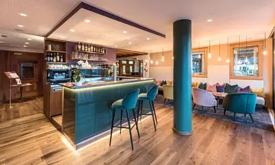a bar in a restaurant with blue bar stools at Marini's giardino Hotel in Tirolo