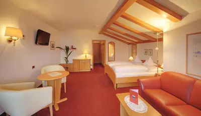 a hotel room with a bed and a couch at Marini's giardino Hotel in Tirolo