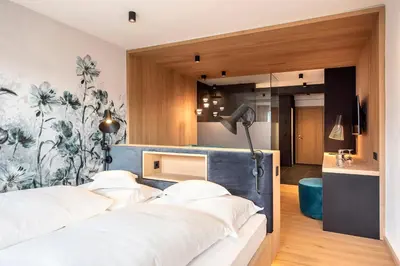 a bedroom with a bed with white pillows at Marini's giardino Hotel in Tirolo