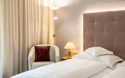a hotel room with a bed and a chair at Marini's giardino Hotel in Tirolo
