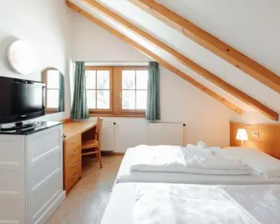 a bedroom with a bed and a desk with a television at Hotel Corno Bianco in Nova Ponente