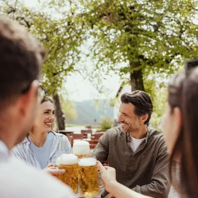 a group of people sitting around a table drinking beer at Hotel Corno Bianco in Nova Ponente