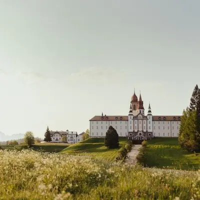 a large building on a hill with a grassy field at Hotel Corno Bianco in Nova Ponente