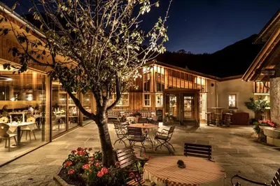 a patio with a tree and tables and chairs at Zum Alten Moar in Bressanone