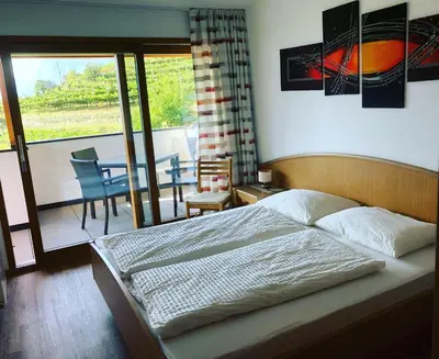a bedroom with a bed and a balcony with a table at Finkenhof: Ferienwohungen - Urlaub auf dem Bauernhof in Termeno