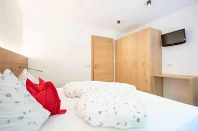 a bedroom with a white bed with red pillows at Haus Christian in Nova Levante