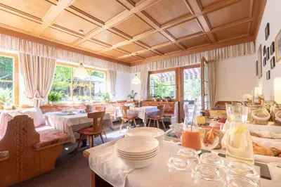 a restaurant with white tables and chairs and windows at Haus Christian in Nova Levante