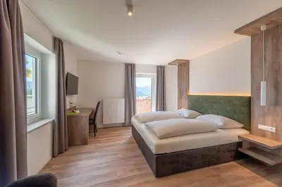 a bedroom with a bed and a desk and a window at Beim Sarner in Caldaro