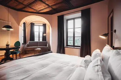 a bedroom with a large white bed and a chair at Castel Maurn Dolomites in San Lorenzo di Sebato