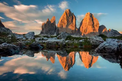 a group of tall rocks with a reflection in the water at Castel Maurn Dolomites in San Lorenzo di Sebato