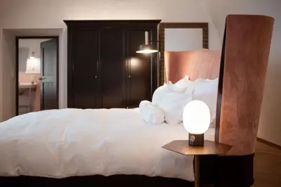 a bedroom with a large white bed and a lamp at Castel Maurn Dolomites in San Lorenzo di Sebato