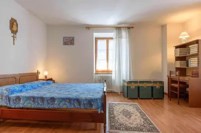 a bedroom with a bed and a desk and a window at Appartamento Da Vittoria Valda Val di Cembra in Valda