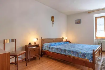 a bedroom with a bed and a table and a chair at Appartamento Da Vittoria Valda Val di Cembra in Valda