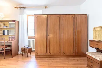 a large wooden cabinet in a room with a table at Appartamento Da Vittoria Valda Val di Cembra in Valda