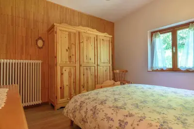 a bedroom with a bed and a wooden cabinet at Al Faggio Ponciach Altavalle OSPITAR in Sover