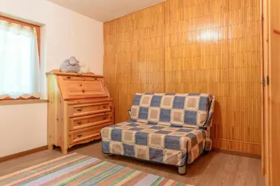 a bedroom with a chair and a wooden wall at Al Faggio Ponciach Altavalle OSPITAR in Sover