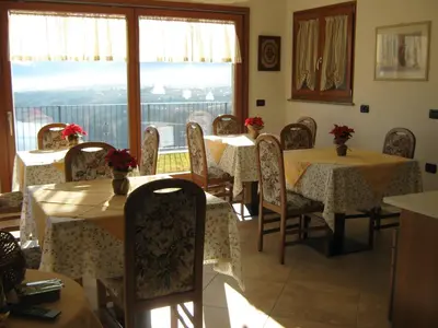 a dining room with tables and chairs and a window at Agritur Vista Lago in Revò