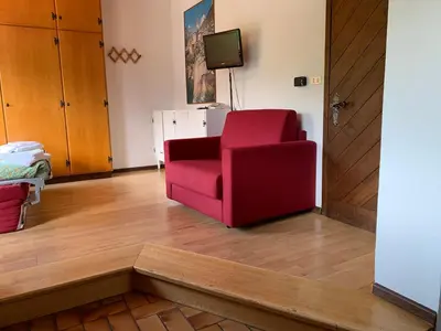 a living room with a red couch and large windows at Residence Trunka Lunka in Cavalese