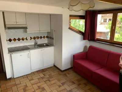 a living room with a red couch and a kitchen at Residence Trunka Lunka in Cavalese