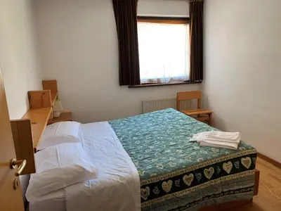 a bedroom with a large bed with a window at Residence Trunka Lunka in Cavalese