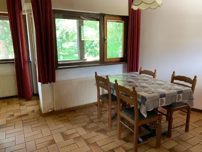 a dining room with a table and chairs and windows at Residence Trunka Lunka in Cavalese