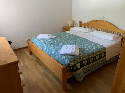 a bedroom with a wooden bed with two towels on it at Residence Trunka Lunka in Cavalese