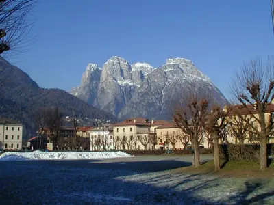 a mountain in the background of a town with trees and buildings at The Bijoux - Dolomites in Agordo