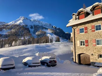 two cars parked in the snow next to a building at Renoviertes Apartment mit Terrasse an der Piste mit kostenlosen WiFi in Carezza al Lago