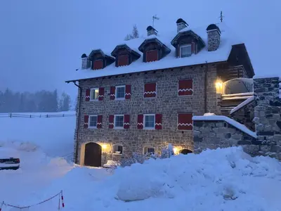 a building with snow on top of it in the snow at Renoviertes Apartment mit Terrasse an der Piste mit kostenlosen WiFi in Carezza al Lago