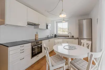 a kitchen with white cabinets and a white table and chairs at Renoviertes Apartment mit Terrasse an der Piste mit kostenlosen WiFi in Carezza al Lago
