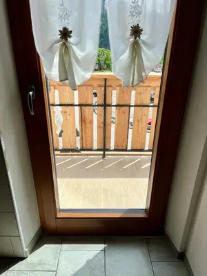 a door with a window with white curtains at My Dolomites Home in Livinallongo del Col di Lana