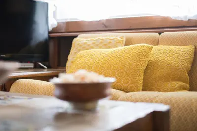 a couch with yellow pillows and a table with a bowl on it at Casa vacanze 5 Torri in Cortina dʼAmpezzo