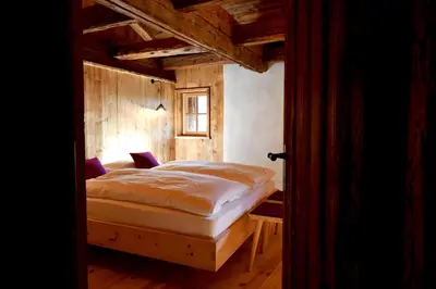 a bedroom with a bed in a room with wooden walls at Haidnerhof in Bressanone