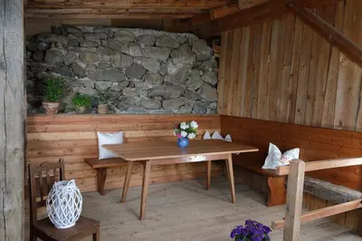 a wooden room with a table and a stone wall at Glögglhof in Lana