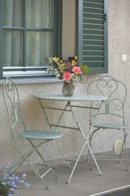 a table with a vase of flowers and two chairs at Glögglhof in Lana