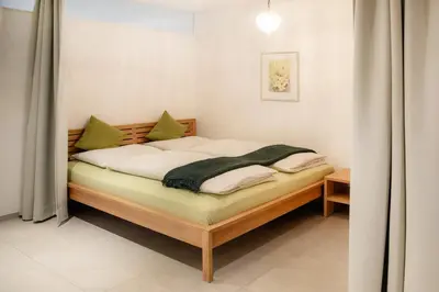a small bedroom with a bed with white sheets and green pillows at Puenlandhof in Brunico