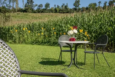 two chairs and a table with a vase of flowers on it at Puenlandhof in Brunico